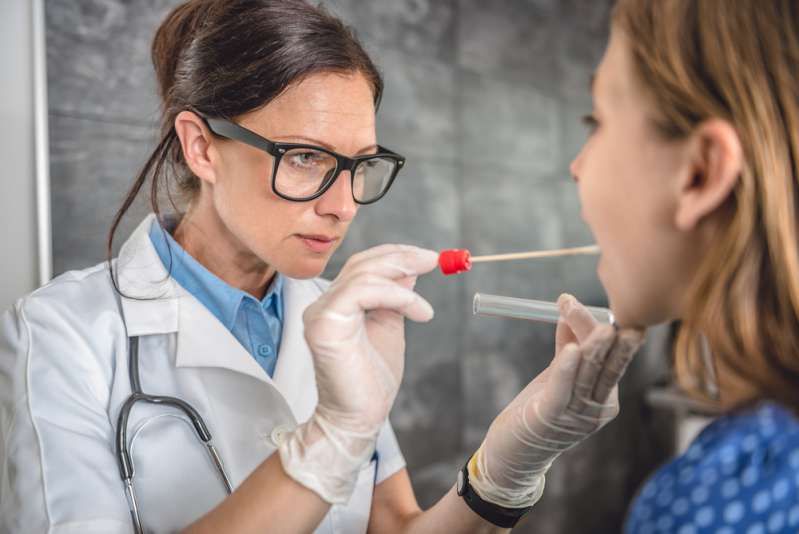 舌の信号の健康問題に歯がマークを付けるのはいつですか？女性の小児科医が綿棒を使用して患者からサンプルを採取します